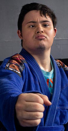 Foto de homem de pele branca, que tem síndrome de down, vestindo kimono.